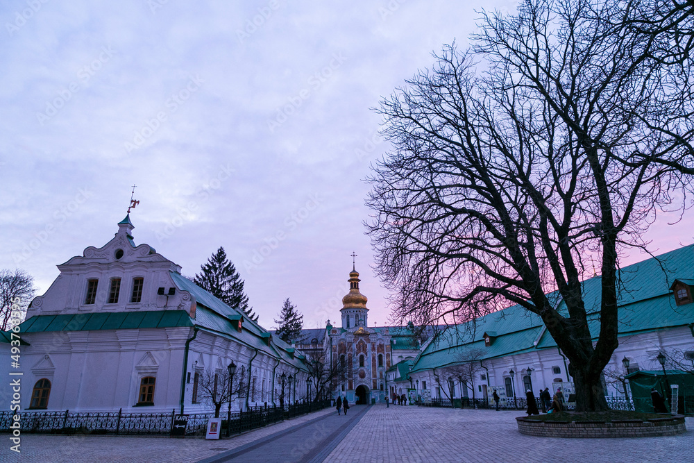 Medieval Gate Church of the Trinity of Kyiv Pechersk Lavra. View of east facade from the monastery side on a background of blue sky with clouds in winter. 
