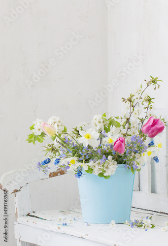 spring flowers in vintage white interior with old wooden bench