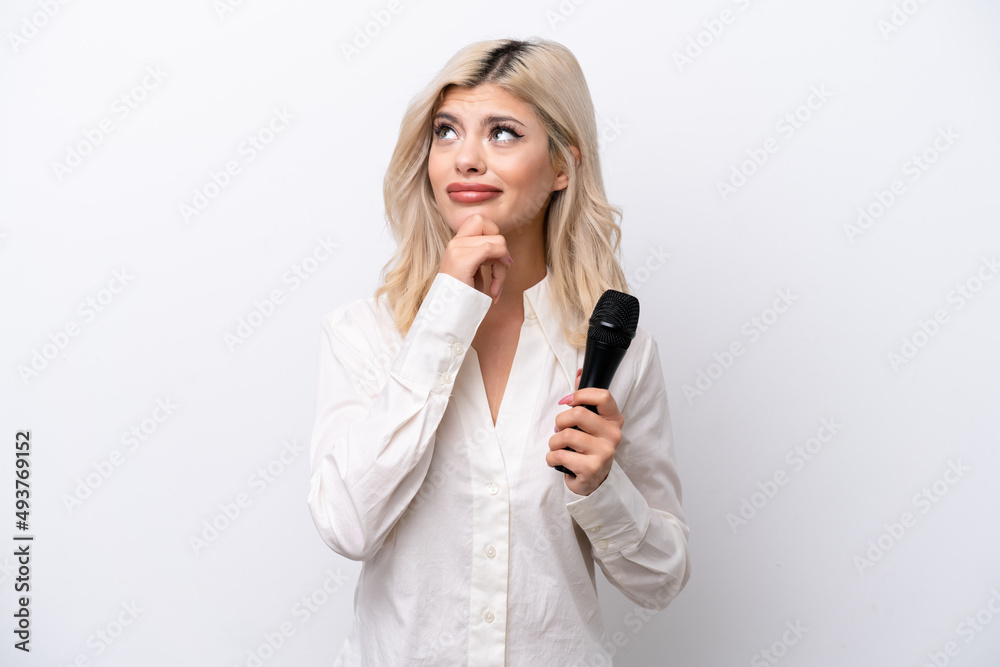 Young singer woman picking up a microphone isolated on white background and looking up Young singer woman picking up a microphone isolated on white background and looking up