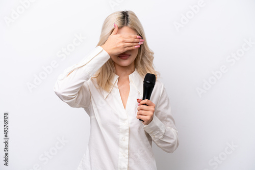 Young singer woman picking up a microphone isolated on white background covering eyes by hands. Do not want to see something