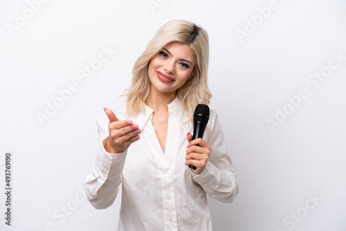 Young singer woman picking up a microphone isolated on white background shaking hands for closing a good deal
