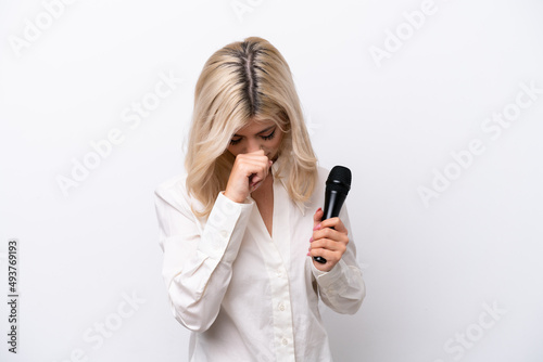 Young singer woman picking up a microphone isolated on white background having doubts