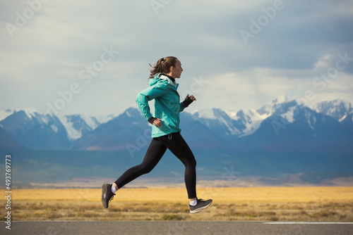 Fototapeta Naklejka Na Ścianę i Meble -  Sports girl is engaged in jogging on the highway against the background of mountains