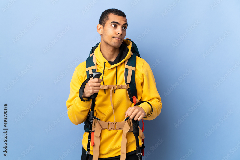 African American man with backpack and trekking poles over isolated background making doubts gesture looking side African American man with backpack and trekking poles over isolated background making doubts gesture looking side