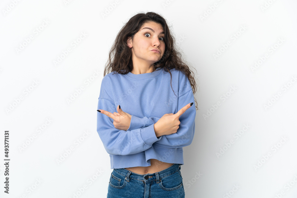 Teenager Russian girl isolated on white background pointing to the laterals having doubts Teenager Russian girl isolated on white background pointing to the laterals having doubts