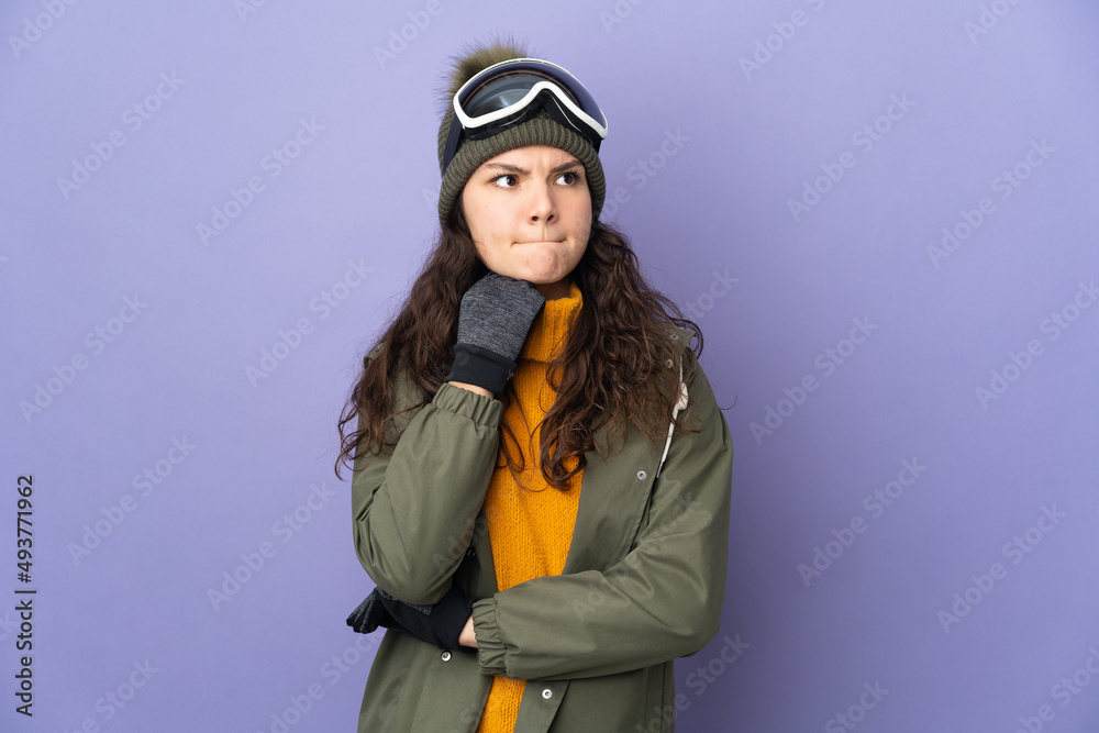 Teenager Russian girl with snowboarding glasses isolated on purple background having doubts and thinking
