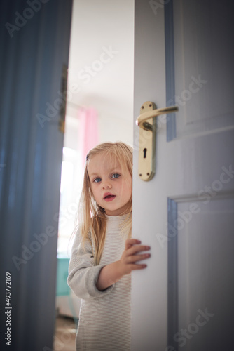Knock knock, whos there. Shot of an adorable little girl opening a door at home.