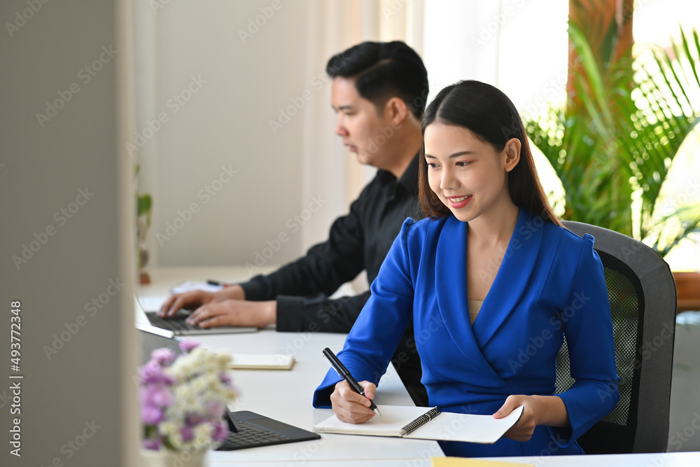 Fototapeta premium A portrait of a businessman and a businesswoman sitting in the office working on a data, documents and a tablet on the table with colleague, for business, finance and technology concept.