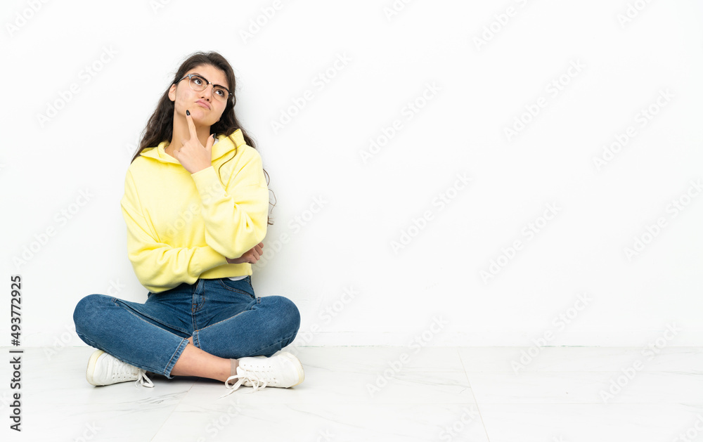 Teenager Russian girl sitting on the floor having doubts while looking up Teenager Russian girl sitting on the floor having doubts while looking up