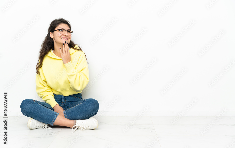 Teenager Russian girl sitting on the floor looking up while smiling