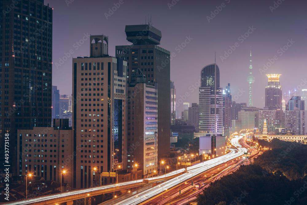 Urban overpasses with lights on at night and the urban background in the distance