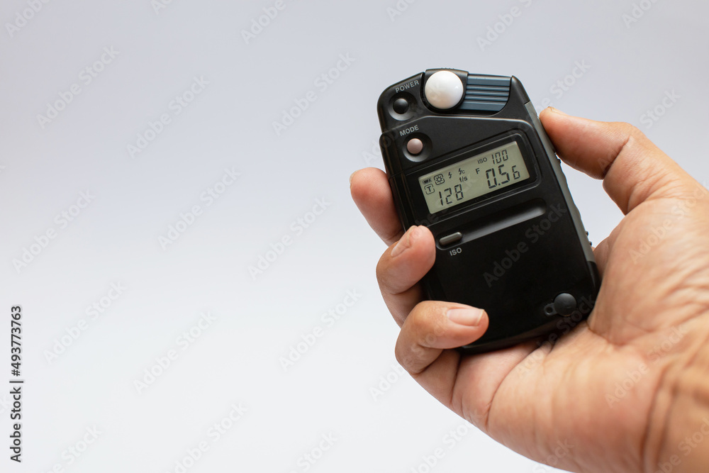 Meter for measuring light intensity in hand isolated on white. photographic equipment white background Meter for measuring light intensity in hand isolated on white. photographic equipment white background