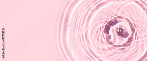 Drops on pink water background under sunlight. Top view, flat lay. Banner