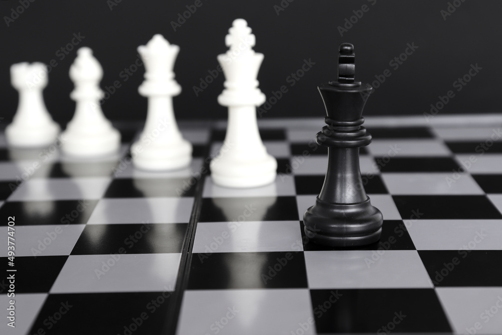 The king in a battle chess game stands on a chessboard with a black isolated background. Business Leadership Ideas.
