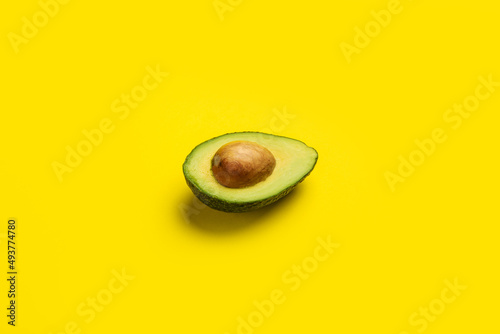 fresh ripe half of an avocado on a bright yellow background. Top view, flat lay