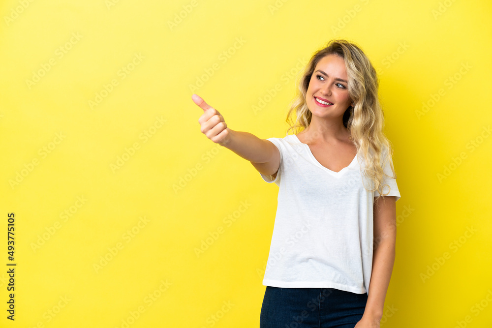 Young Brazilian woman isolated on yellow background giving a thumbs up gesture Young Brazilian woman isolated on yellow background giving a thumbs up gesture