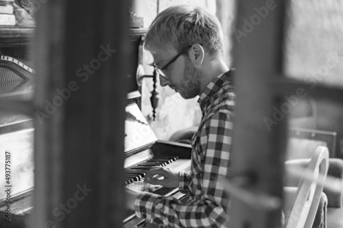 Melancholischer Piano Spieler spielt Klavier - Ansicht durch Fenster auf Geschehen schwarz weiß photo