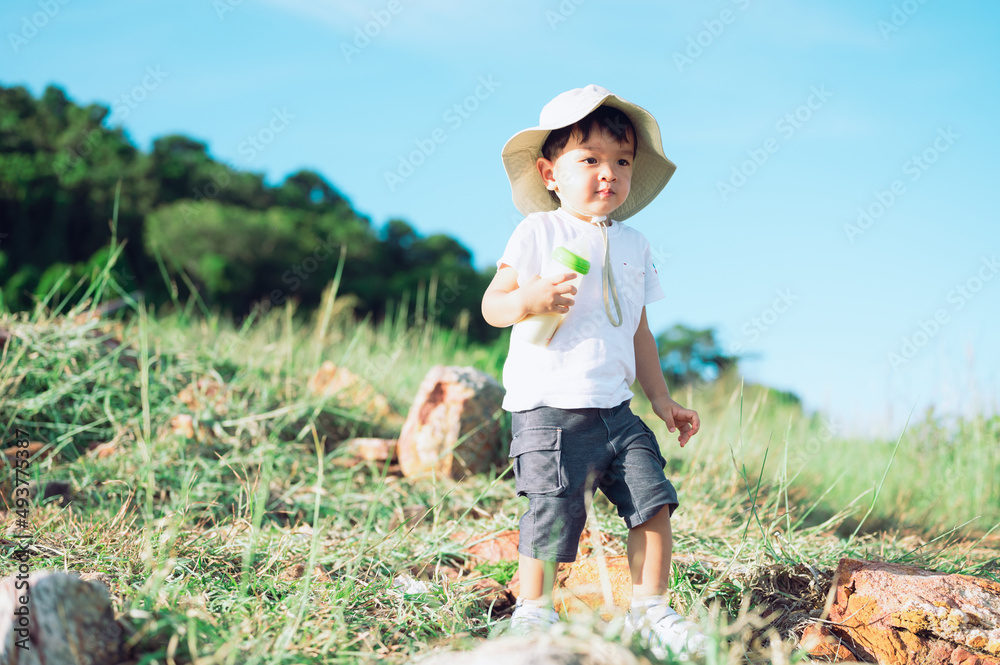 Asian little boy hiking in scenic mountains with baby bottle