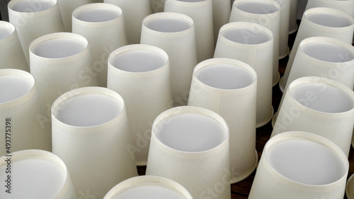 Row of white disposable eco friendly paper cup for coffee or hot beverage on dark backdrop. Selective focus.