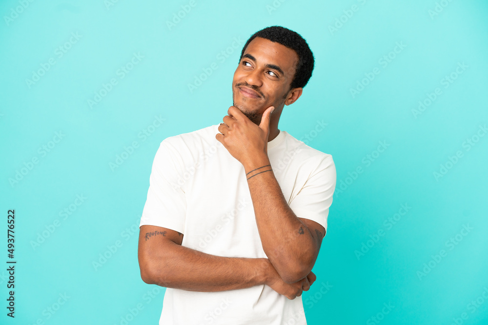 African American handsome man on isolated blue background looking up while smiling African American handsome man on isolated blue background looking up while smiling