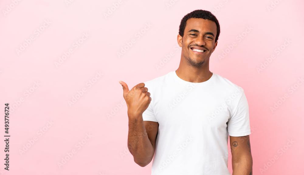 African American man on copyspace pink background pointing to the side to present a product African American man on copyspace pink background pointing to the side to present a product