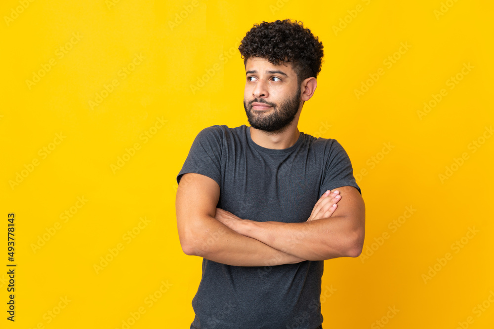 Young Moroccan man isolated on yellow background making doubts gesture while lifting the shoulders Young Moroccan man isolated on yellow background making doubts gesture while lifting the shoulders
