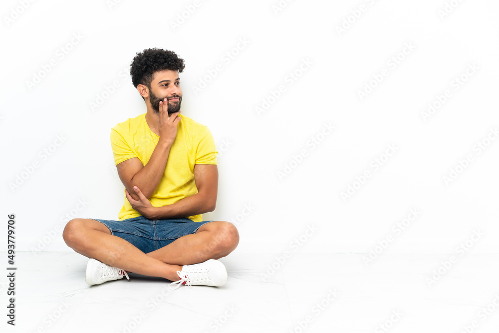 Young Moroccan handsome man sitting on the floor over isolated background thinking an idea while looking up Young Moroccan handsome man sitting on the floor over isolated background thinking an idea while looking up