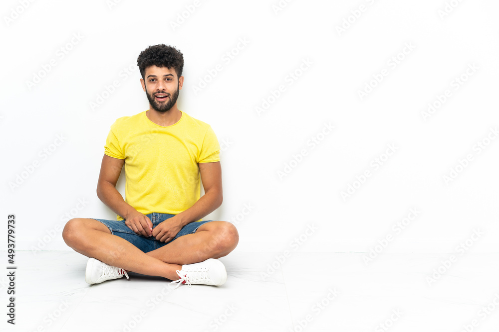Young Moroccan handsome man sitting on the floor over isolated background with surprise facial expression Young Moroccan handsome man sitting on the floor over isolated background with surprise facial expression