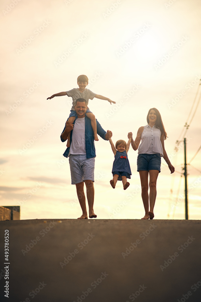 Fototapeta premium We love bonding over long walks. Shot of a young family taking a walk down the road outside.