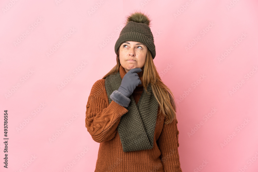 Middle age woman with winter hat isolated on pink background and looking up Middle age woman with winter hat isolated on pink background and looking up