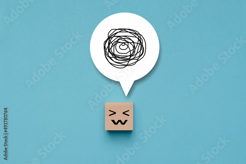 Wooden cube with unhappy face with a tangle of thoughts in its head, wood block with a emotion stress face and confused thoughts , depressed and worry for distress