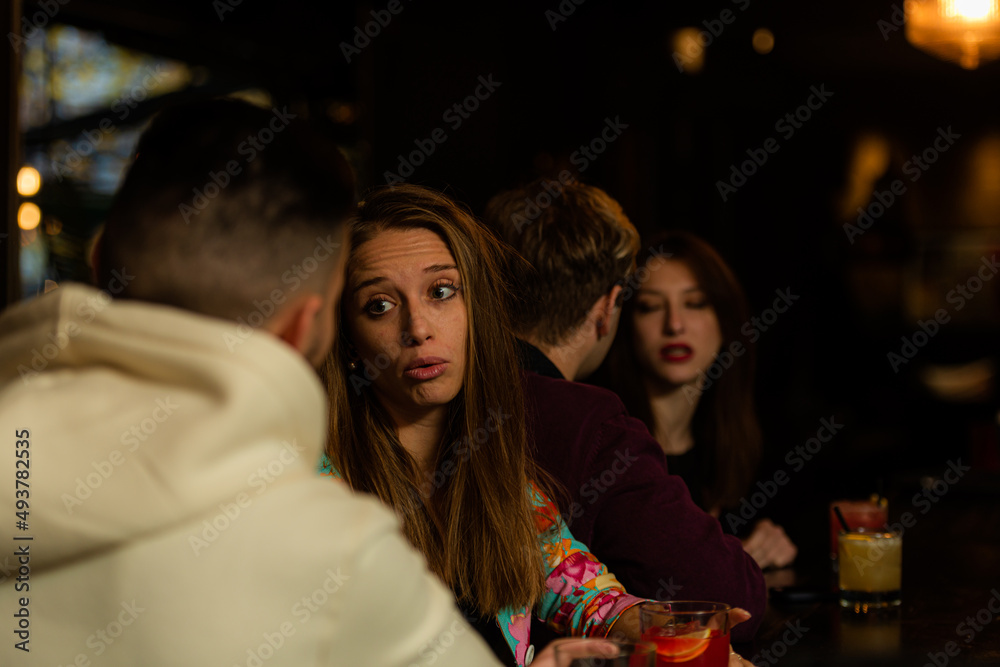 Two couples talking on the bar and having a great time while sitting next to each other