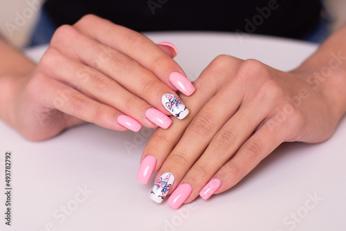 Beautiful female hands with creative manicure nails with unicorn design, pink gel polish