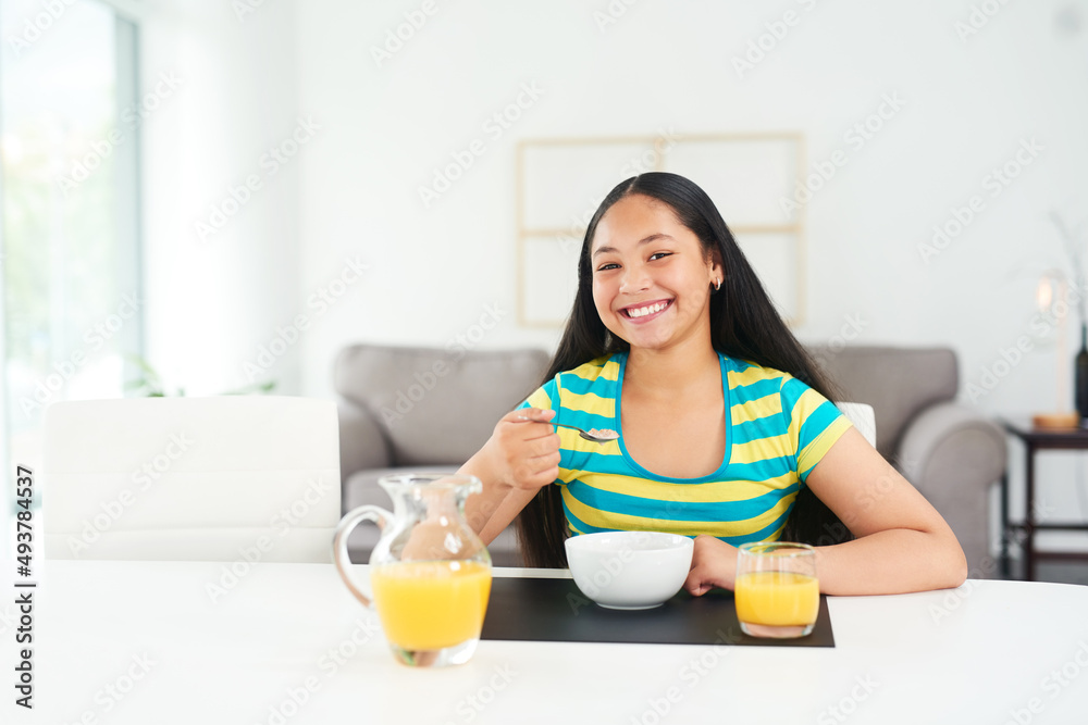The most important meal of the day. Portrait of a happy young girl enjoying a healthy breakfast at home.