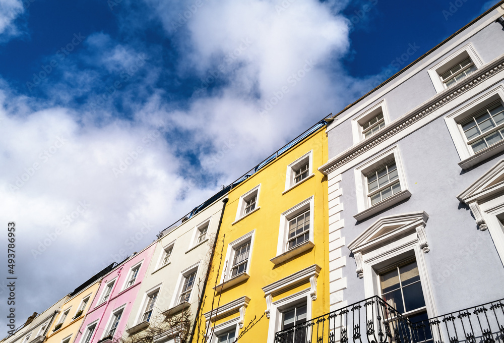 Fototapeta premium Colourful terraced townhouses with summer sky background and space for text. The area of Notting Hill, London, is famous for streets of houses with brightly painted exteriors.
