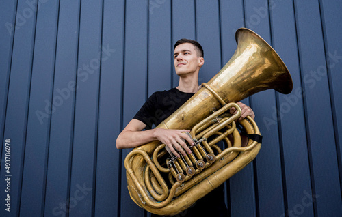 Young street musician playing the tuba near the big blue wall photo