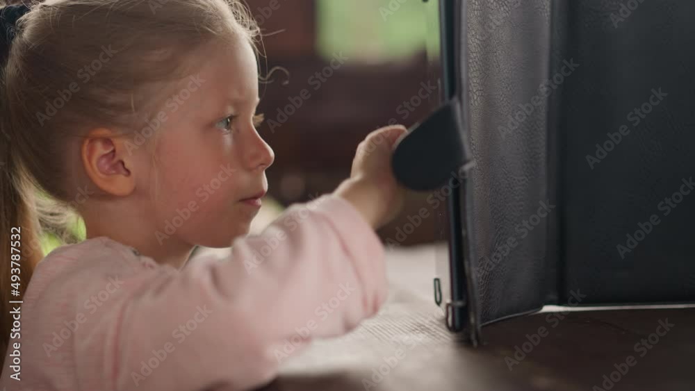 Calm concentrated blonde little girl in warm jacket draws picture on tablet computer by finger in eco hotel cafe extreme close side view slow motion Calm concentrated blonde little girl in warm jacket draws picture on tablet computer by finger in eco hotel cafe extreme close side view slow motion