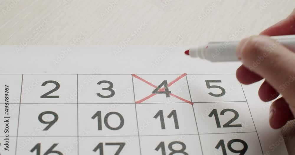 Man's hand Write down the 4th day on the paper calendar using a red pen. Very important date in the calendar. Signing a day on a calendar. Calendar 4th date of the month cut.