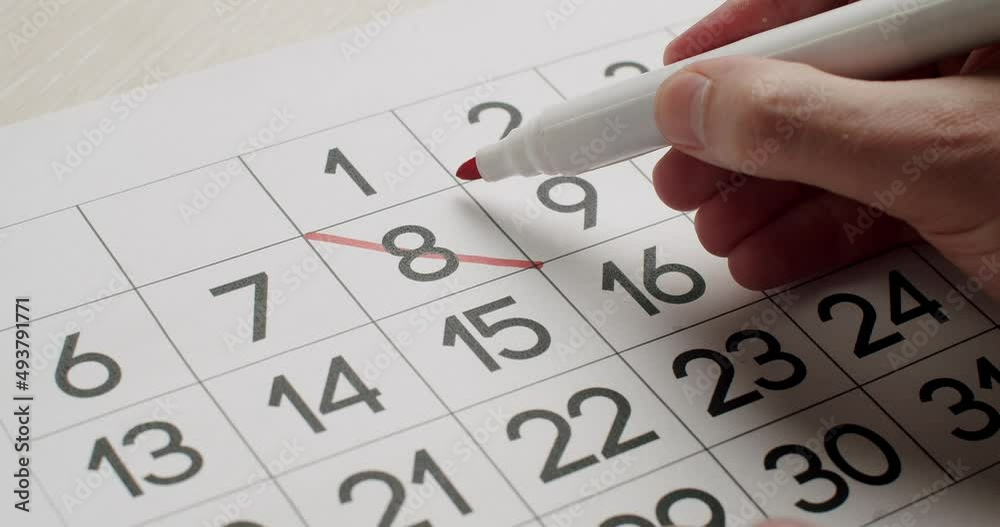 Man's hand Write down the 23th day on the paper calendar using a red pen. Very important date in the calendar. Signing a day on a calendar. Calendar 23th date of the month cut.