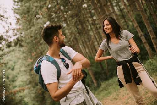 Couple of hikers with backpacks walk through the forest