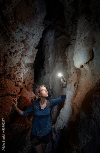 Young woman exploring a cave digged in the mountain.