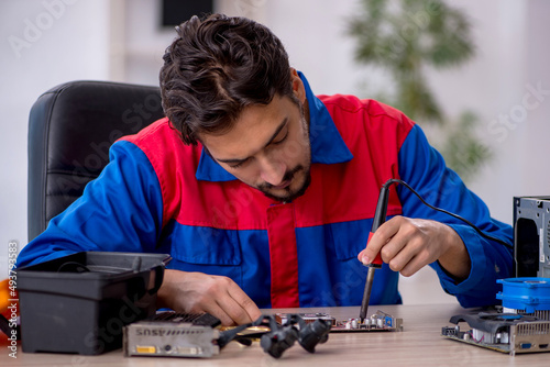 Young male repairman repairing computer