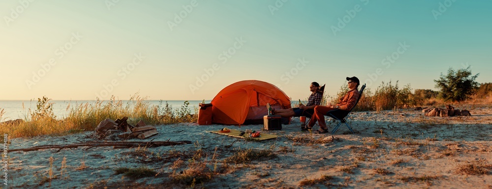 © luengo_ua - Happy young friends resting by the bonfire near tent.
