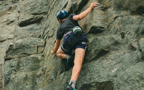 Young man in equipment doing rock climbing outdoors. Training area for outdoor activities. Extreme sport.