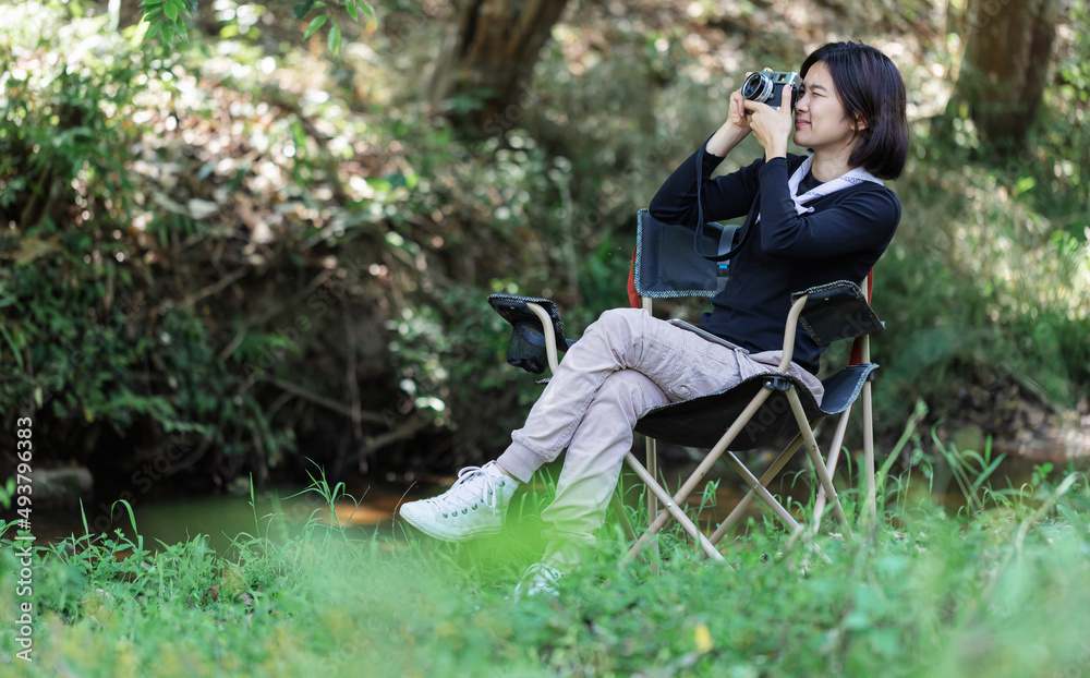 Portrait nature girl photographer relaxing and using camera on the bank of a creek. Portrait nature girl photographer relaxing and using camera on the bank of a creek.