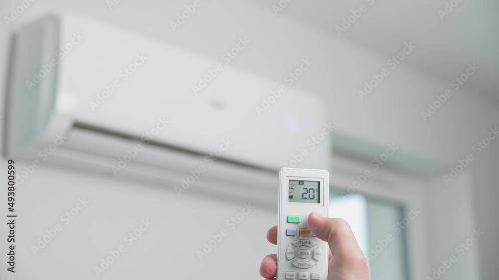 Hand adjusting temperature on air conditioner with remote control, Working air conditioner for comfort temperature in home at hot summer