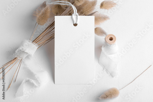 Rectangle white tag mockup on a white background with cotton string and boho decoration, dry plants, element for packing. Label product bohemian mockup copy space for text and natural eco design