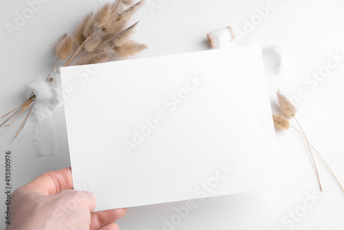 Wedding stationery invitation card mockup 7x5 on white background with boho decor, female hand hold empty card mockup. Minimal bohemian blank mockup, thank you card, greeting card photo