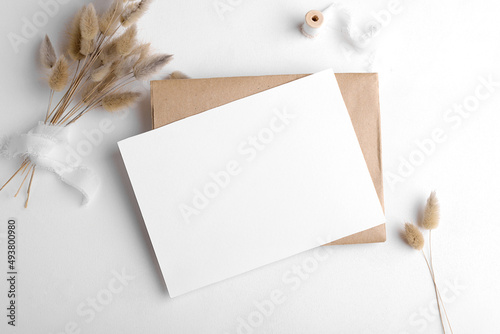 Wedding stationery invitation card mockup 7x5 on white background with envelop and boho decor. Baby shower o bridal shower mockup. Minimal bohemian style blank mockup, thank you card, greeting card