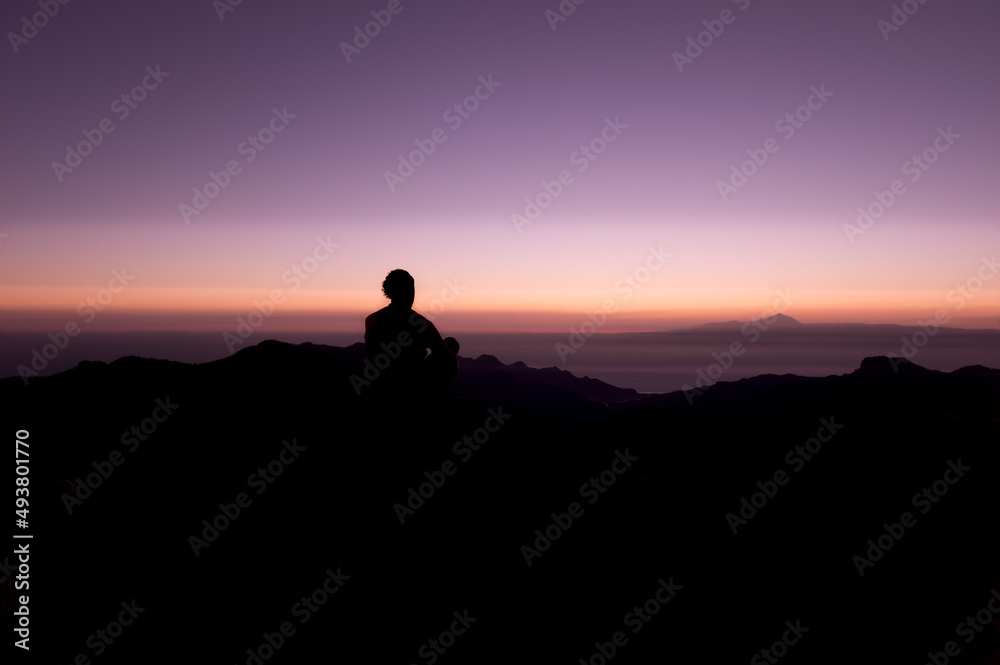 Mann meditiert im Gebirge bei Sonnenuntergang. Blick von Gran Canaria nach Teneriffa zum Pico del Teide.